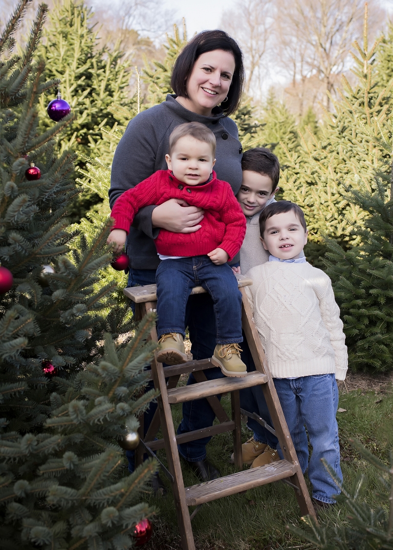 Mother standing with three young sons at christmas tree farm in North Attleboro MA